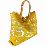Elegant yellow and gold canvas handbag with leather handles, crafted with intricate floral patterns, a stylish accessory from the PurpleBoho specialty bohemian clothing store.