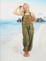 a woman standing on a beach wearing a green tie dye jumpsuit