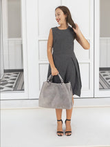 Gray braided leather handbag held by model, elegant setting