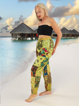 Model wearing green boho pants with geometric patterns, standing on a beach with the ocean in the background. The pants are loose and comfortable, featuring drawstrings at the waist and ankles for a relaxed fit.
