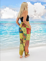 Model wearing green boho pants with geometric patterns, standing on a beach with the ocean in the background. The pants are loose and comfortable, featuring drawstrings at the waist and ankles for a relaxed fit.