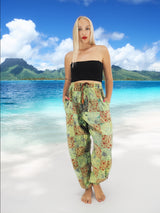 Model wearing green boho pants with geometric patterns, standing on a beach with the ocean in the background. The pants are loose and comfortable, featuring drawstrings at the waist and ankles for a relaxed fit.