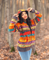 a woman in a colorful jacket standing in a forest