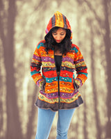 a woman in a colorful jacket standing in front of trees