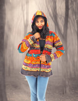 a woman in a colorful jacket standing in a forest