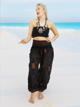a woman standing on a beach wearing a black top and pants