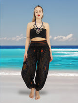 a woman standing on a beach wearing a black top and pants
