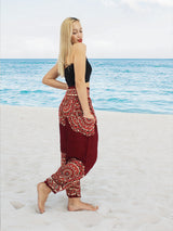 a woman standing on a beach wearing a red pants