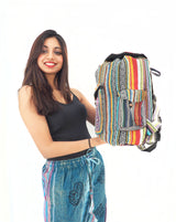 Colorful boho-style backpack with intricate tribal patterns, held by a smiling woman in a black tank top against a white background.