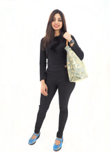 Stylish canvas handbag with leather handles, made in Italy, displayed on a female model wearing a black outfit.