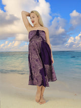 a woman in a purple dress standing on a beach