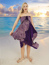 a woman in a purple dress standing on a beach