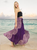 a woman standing on a beach wearing a purple skirt