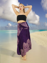 a woman standing on a beach wearing a purple skirt