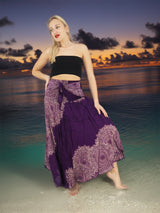 a woman standing on a beach in a purple skirt