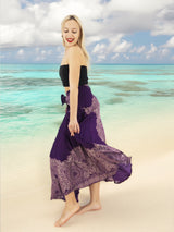 a woman standing on a beach in a purple dress