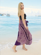 a woman standing on a beach wearing a purple skirt