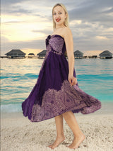 a woman in a purple dress standing on a beach