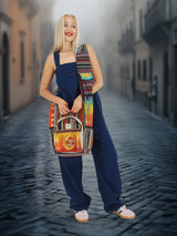 Ethnic-inspired handmade cotton hemp cross body bag with bold colors and a front pocket, carried by a smiling model in a foggy street.