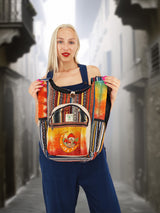 Handmade boho cross body bag with a unique embroidered design, held up by a model to showcase its spacious front pocket.