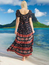 a woman in a long dress standing on a beach