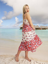 a woman in a red and white dress standing on a beach