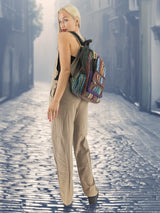 Vintage hippie-style handmade cotton hemp backpack with colorful patterns, carried by a model in a foggy old-town street. Ideal for school and outdoor adventures.