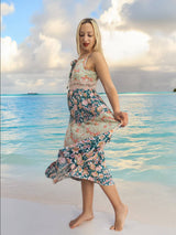 a woman in a floral dress walking on the beach
