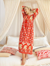 a woman standing on a bed in a red dress