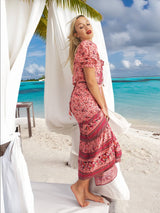 a woman in a pink dress standing on a beach