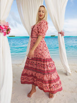 a woman in a pink dress standing on a beach