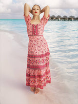a woman in a pink dress standing on a beach