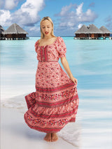 a woman in a pink dress standing on a beach