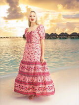 a woman in a pink dress standing on a beach