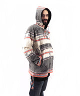 a man wearing a hoodie standing in front of a white background