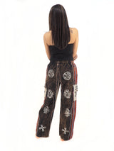 a woman wearing a black top and patterned pants