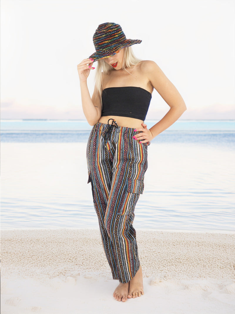 a woman standing on a beach wearing a hat