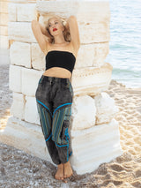 Boho cotton pants with blue details leaning on stone