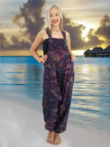 a woman standing on a beach wearing a purple jumpsuit