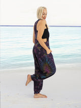 a woman standing on a beach wearing a purple tie dye jumpsuit