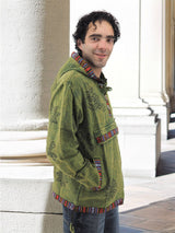 a man standing next to a pillar wearing a green jacket