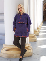 a woman leaning against a pillar in a purple dress