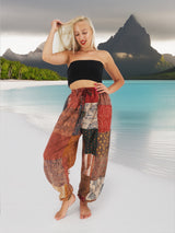 Woman wearing vibrant bohemian cotton patchwork pants standing on the beach with the ocean in the background.