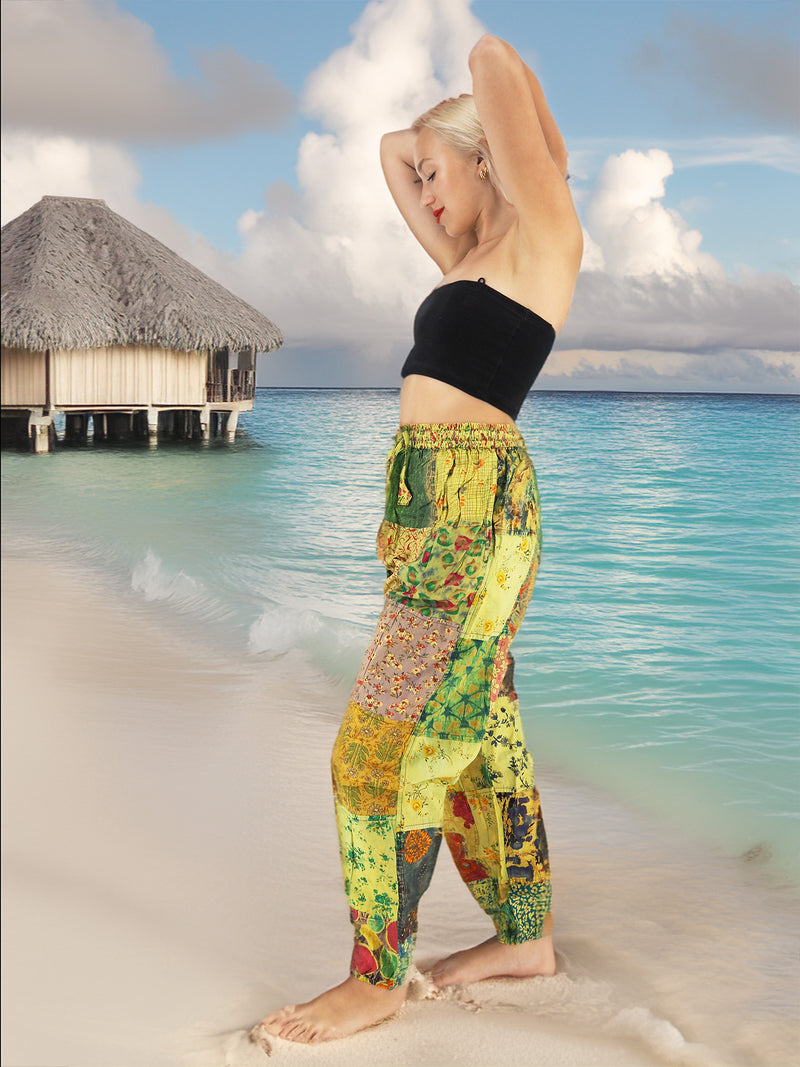 Model wearing green boho pants with geometric patterns, standing on a beach with the ocean in the background. The pants are loose and comfortable, featuring drawstrings at the waist and ankles for a relaxed fit.