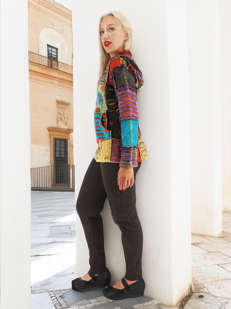 Colorful patchwork bohemian hoodie, handmade 100% cotton, standing in front of historic building