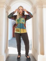 Vibrant patchwork boho hoodie with bold colors and patterns, worn by a stylish model in a grand architectural setting.