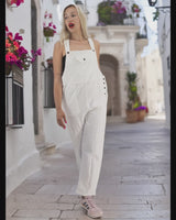 a woman in white overalls is walking down the street